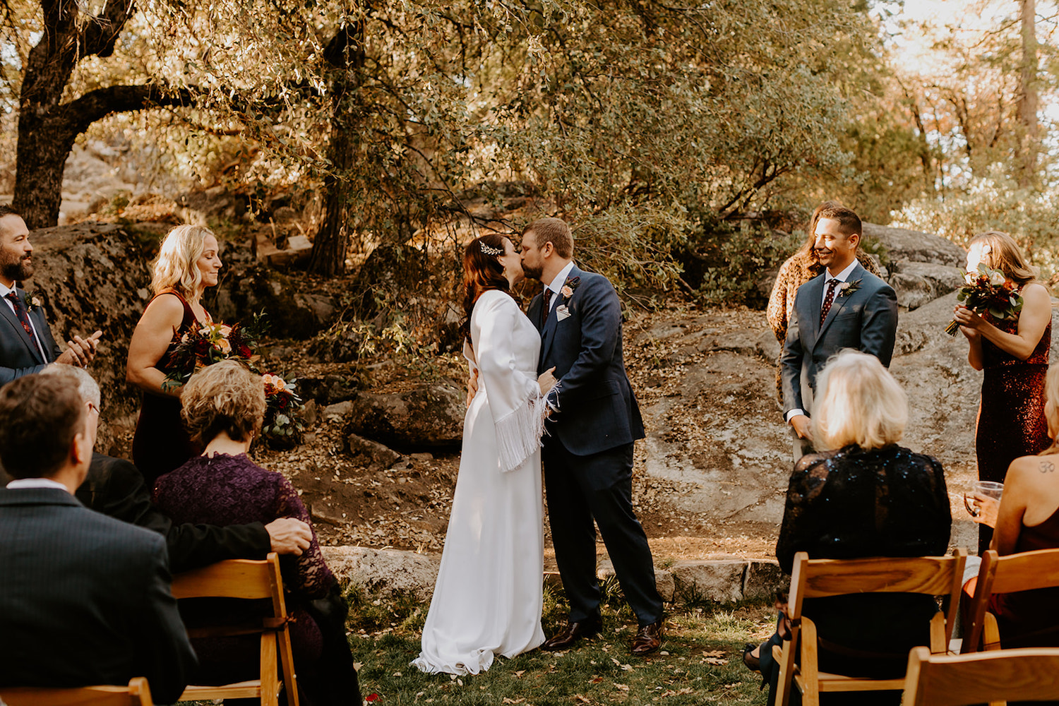 A newlywed couple kisses during their ceremony at their outdoor wedding venue in the bay area, photographed by Maya Lora Photography.