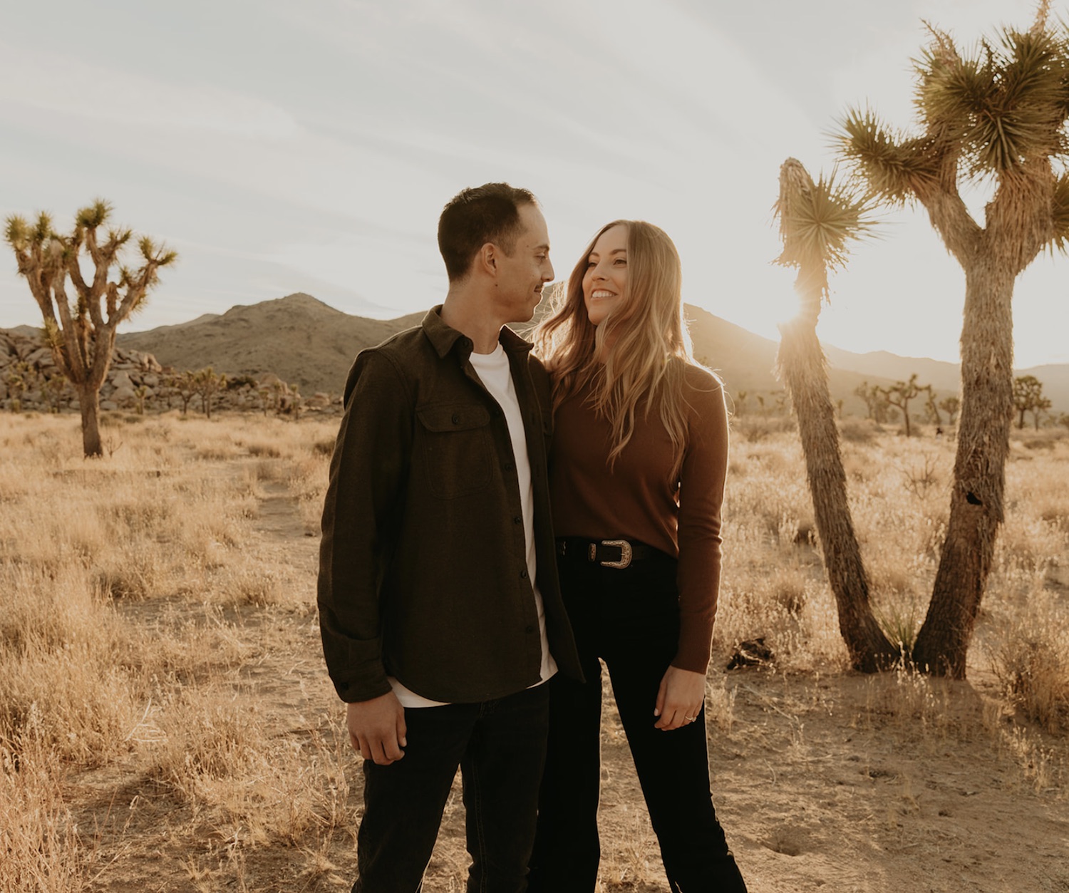 A couple smiles at each other during their golden hour engagement photo shoot in Southern California photographed by Maya Lora Photo.