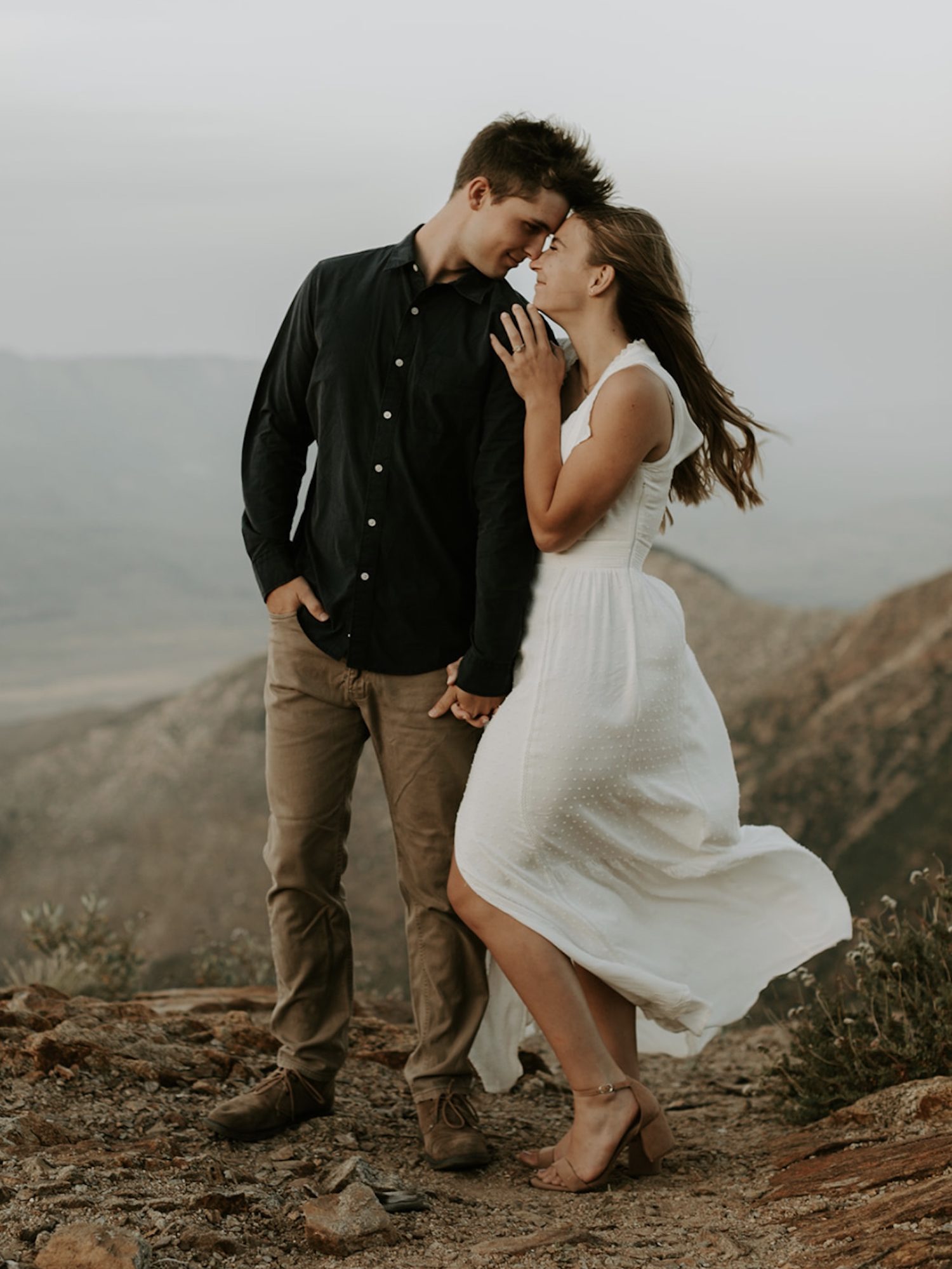 A couple stand cuddling together on the rocks of Laguna Mountain; photo by Maya Lora Photography.