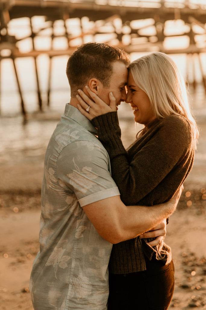 A newly engaged couple embrace by Pier 7 in San Francisco California; image by Maya Lora photo