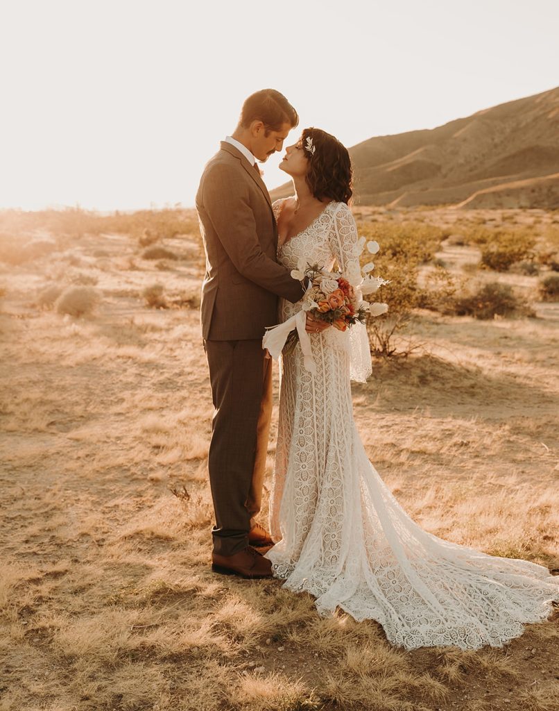 Bride and groom lovingly embrace during sunset of their Joshua Tree wedding