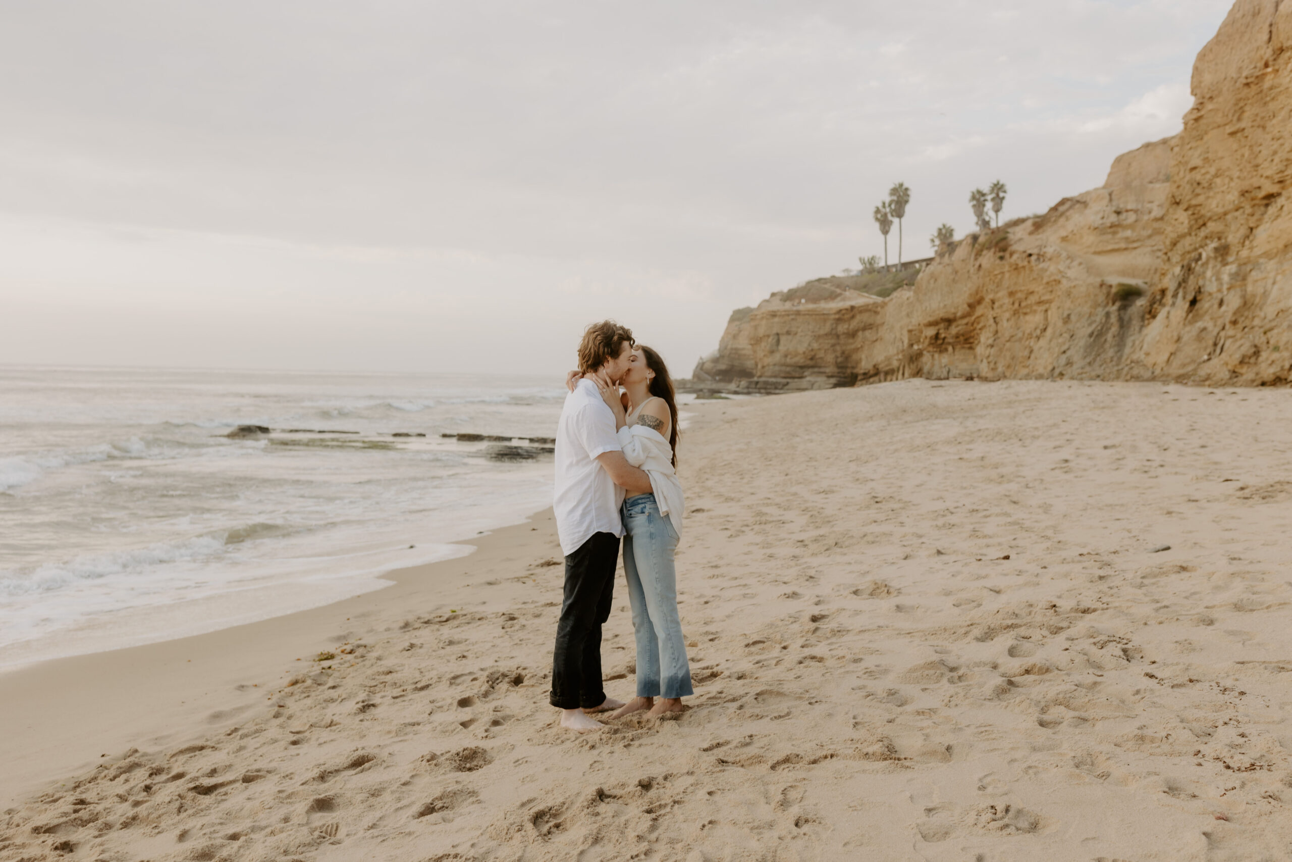Couple embracing at sunset on the beach in San Diego for their engagement photos